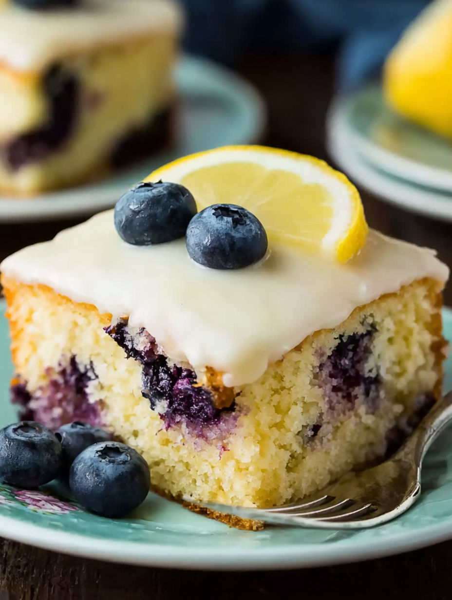 A slice of cake with blueberries and lemon on top.