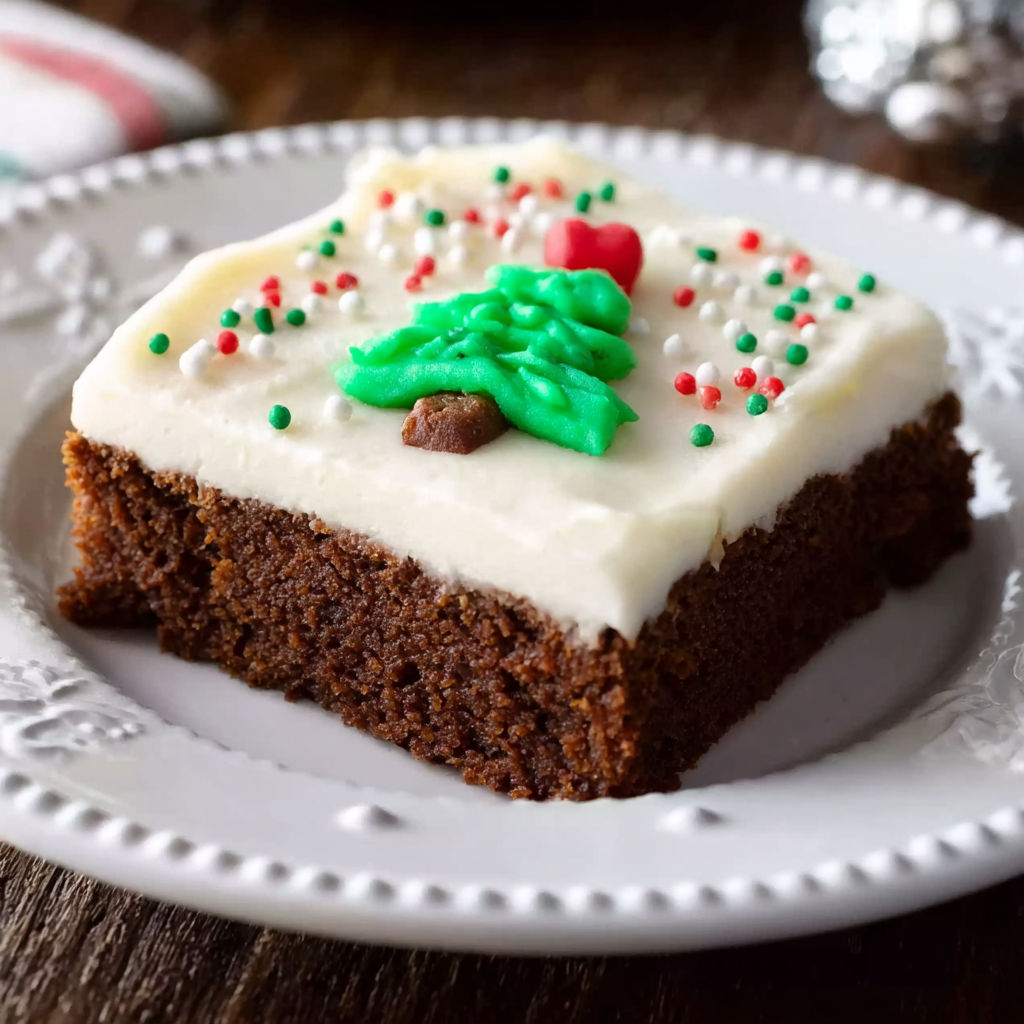 A slice of chocolate cake with white frosting and a green and red decoration.