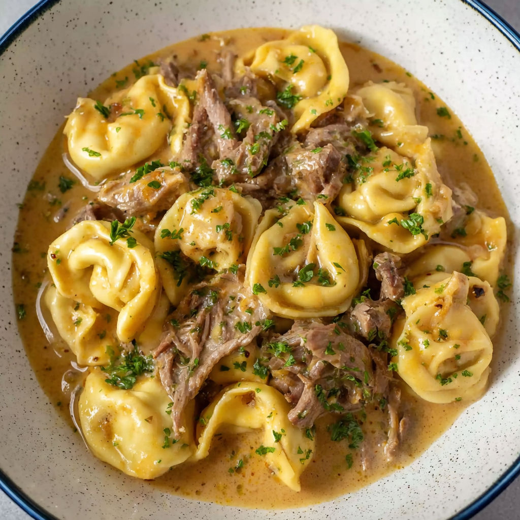 A bowl of pasta with meat and cheese.