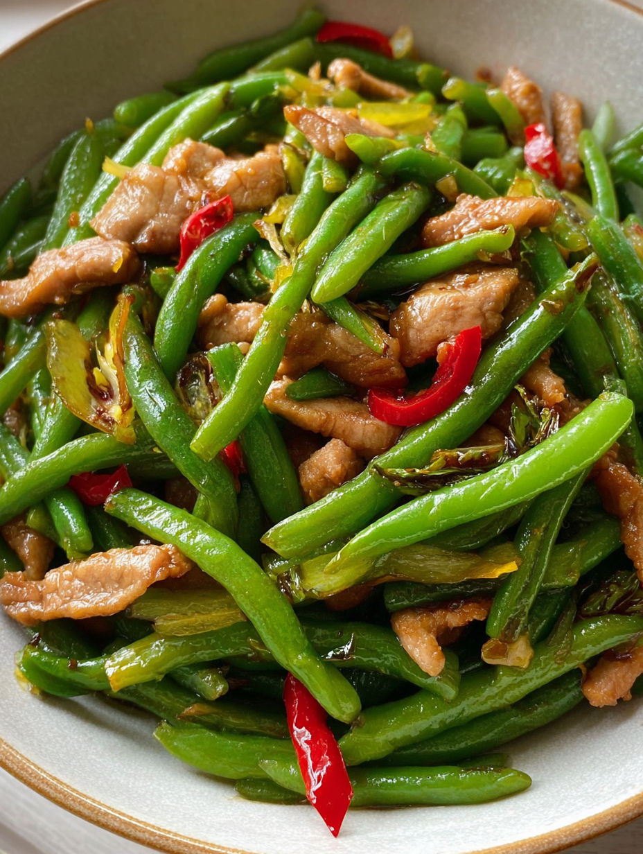 A bowl of stir fry with green beans, meat, and chili.