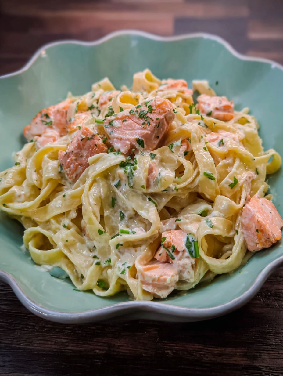 A bowl of pasta with salmon and cream sauce.