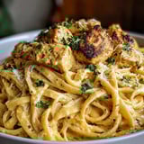 Ein Bild von einer Schüssel mit Cowboy Butter Chicken Linguine, die mit Parmesan und Zwiebeln garniert ist.