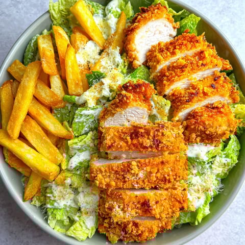 A bowl of food with chicken, fries, and salad.