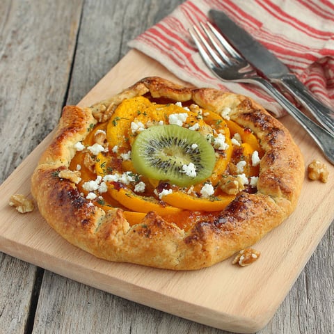 A pizza with kiwi and feta cheese on top.