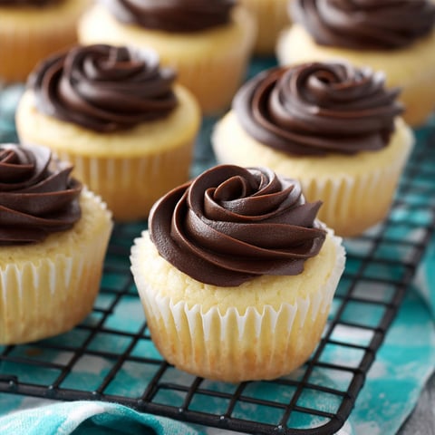 A tray of Boston Cream Pie cupcakes with chocolate frosting.