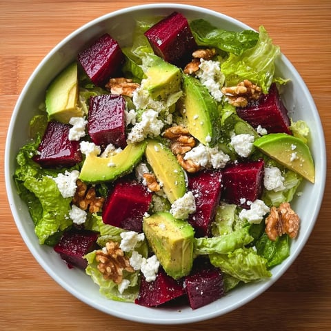 A bowl of salad with avocado, beets, lettuce, and walnuts.