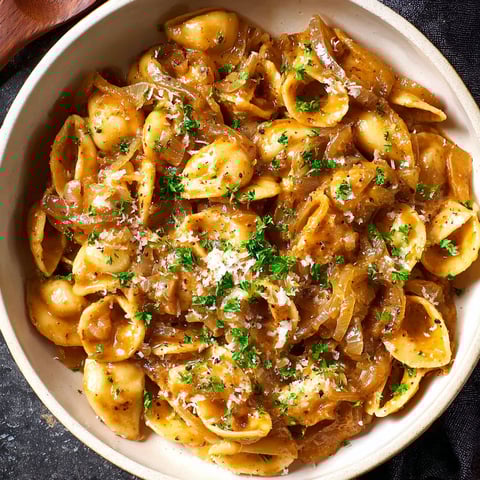 A bowl of pasta with cheese and onions.