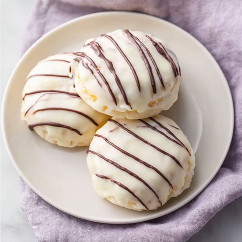 Three white and brown donuts on a plate.