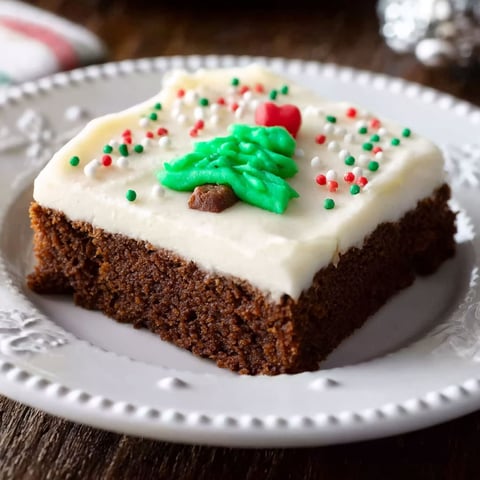 A slice of chocolate cake with white frosting and a green and red decoration.
