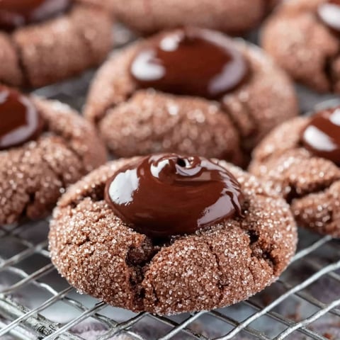 A close up of a chocolate thumbprint cookie.