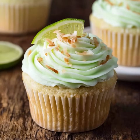 A cupcake with coconut and lime on top.