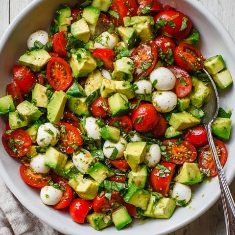 A bowl of tomatoes, mozzarella, and avocado.