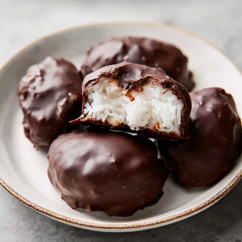 A plate of chocolate covered coconut balls.