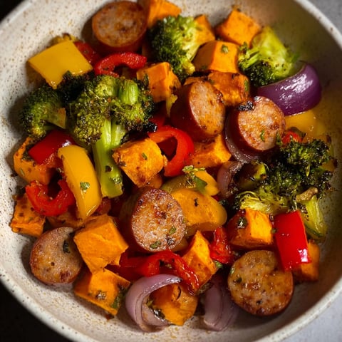 A bowl of food containing sausage, broccoli, and carrots.