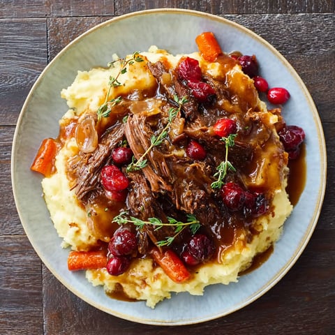 A plate of meat with a sauce and cranberries.