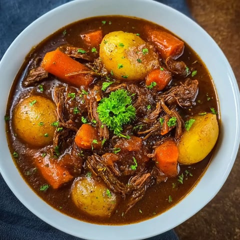 A bowl of beef stew with potatoes and carrots.