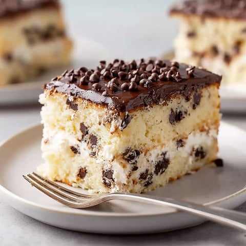 A slice of cannoli cake with chocolate and white frosting.