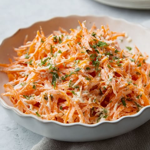 A bowl of shredded carrots with herbs.