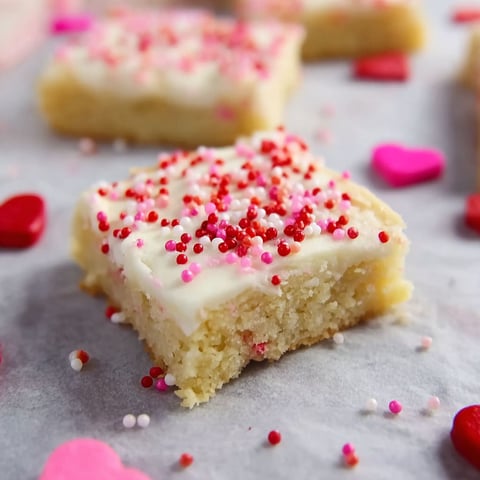 A close up of a sugar cookie with pink and red sprinkles.