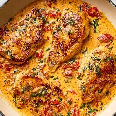 A plate of chicken with tomatoes and herbs.