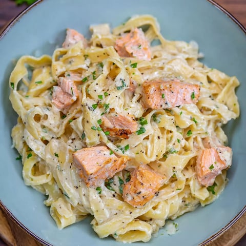 A bowl of pasta with salmon and cream sauce.