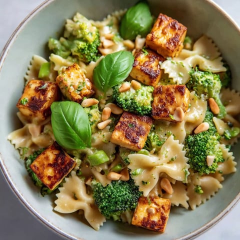 A bowl of pasta with broccoli and tofu.