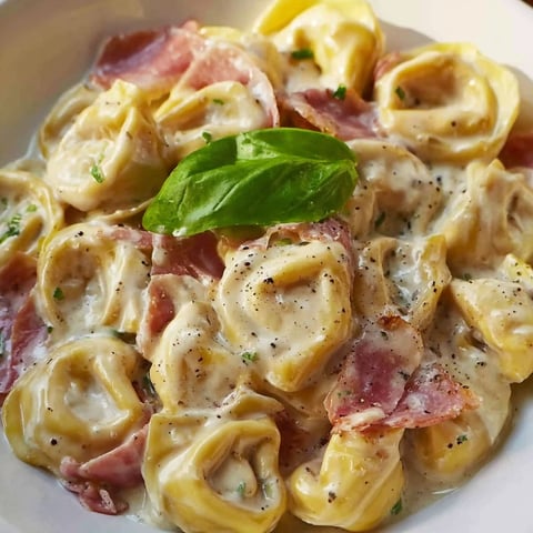 A plate of pasta with meat and greens.